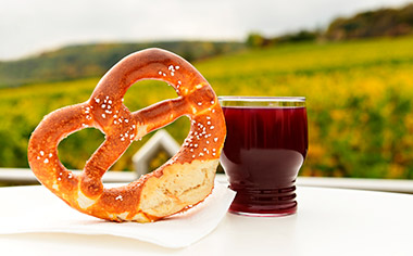 A glass of wine and a pretzel in front of a vineyard in Rudesheim